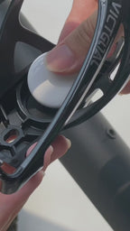Close-up of an AirTag being fitted into the bike bottle cage mount