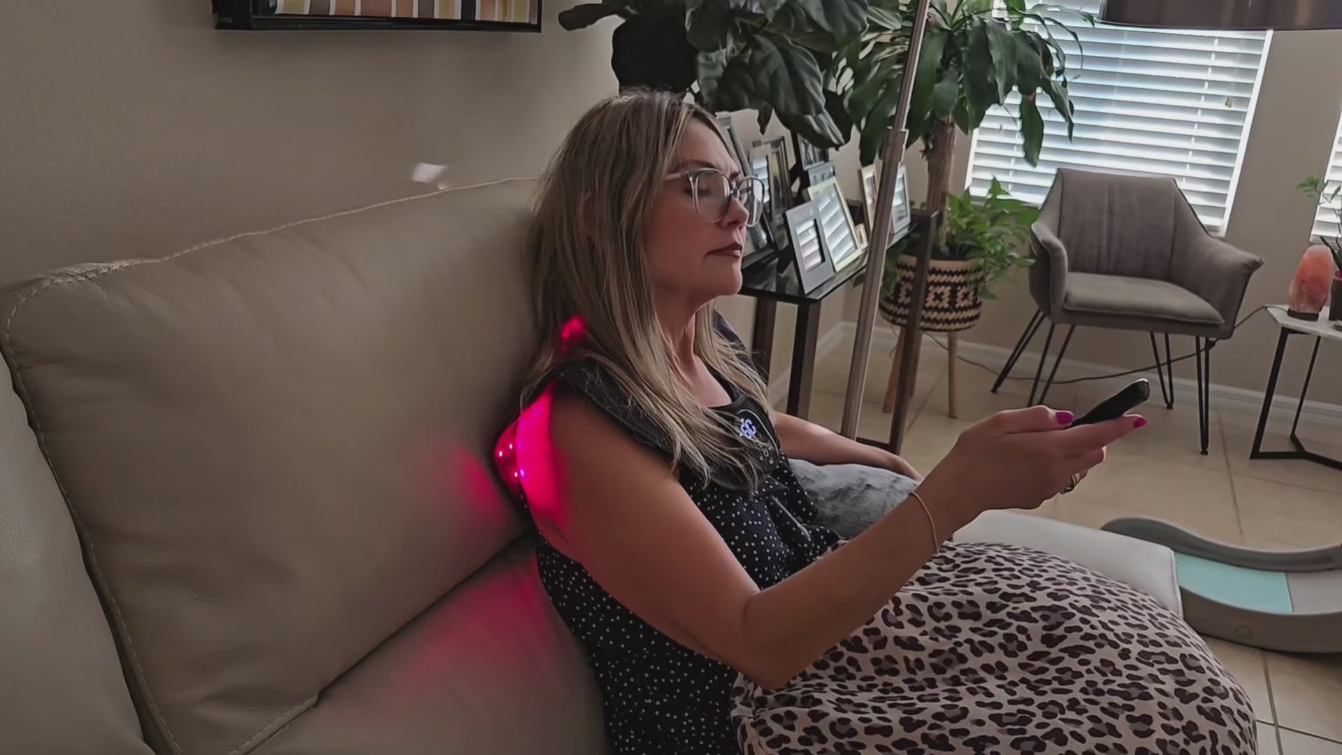 Woman using a red light wrap on her neck and shoulder while seated