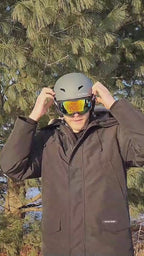 Adult wearing a white ski helmet with reflective snowboard goggles