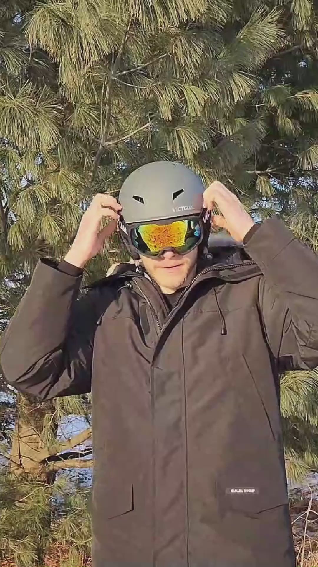 Adult wearing a white ski helmet with reflective snowboard goggles