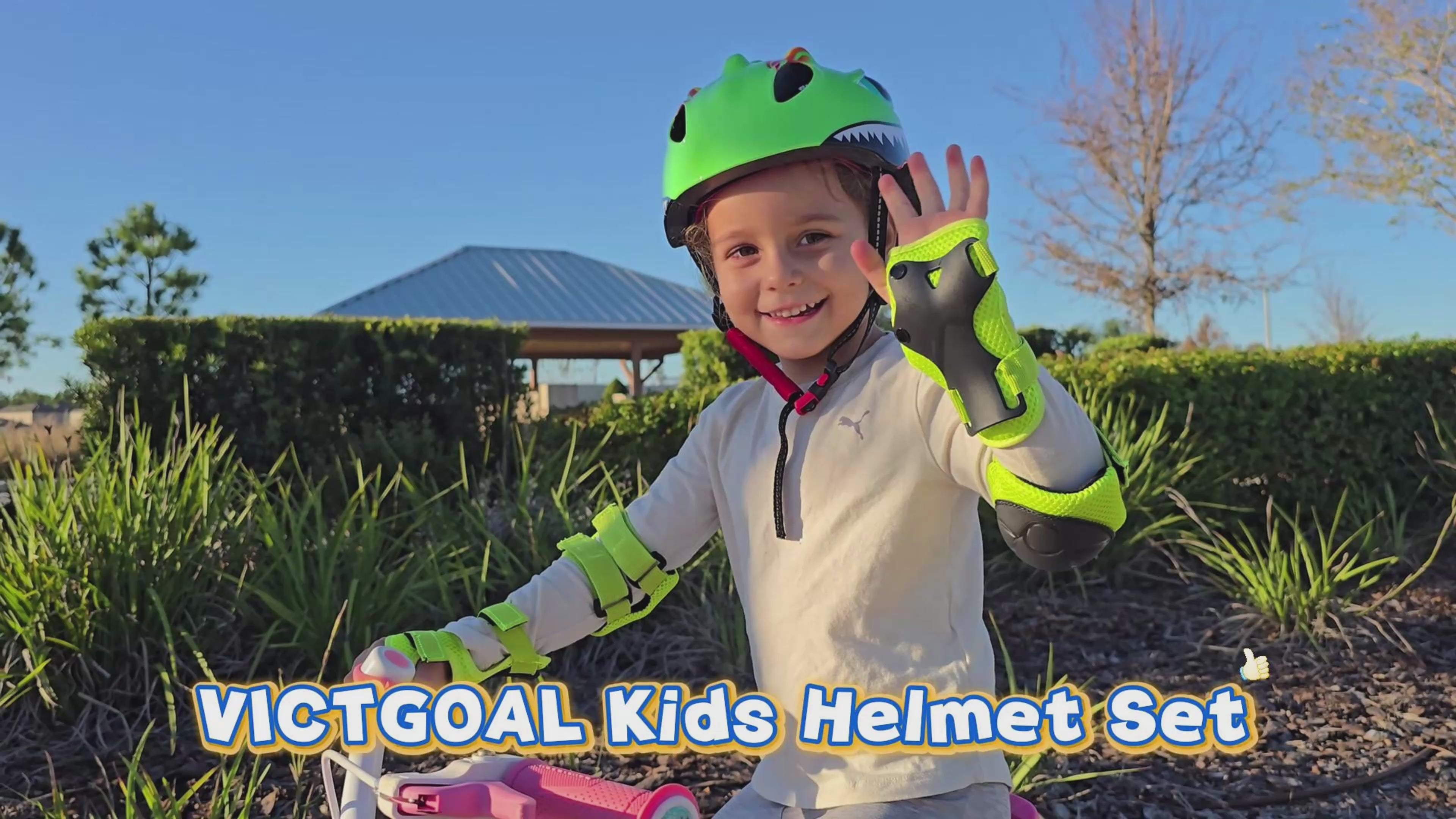 Child wearing a green dinosaur bike helmet and waving outdoors