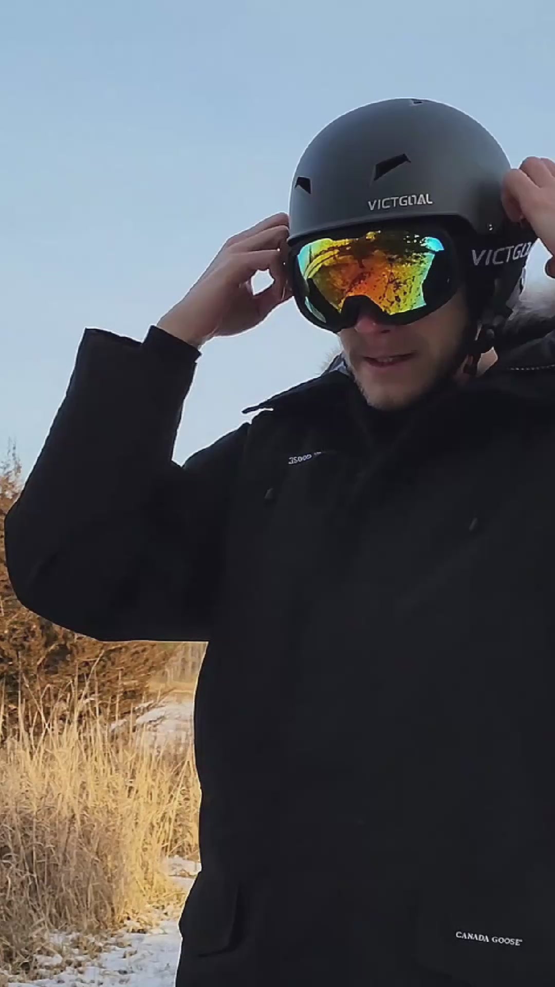 Adult wearing a black ski helmet with reflective OTG snowboard goggles