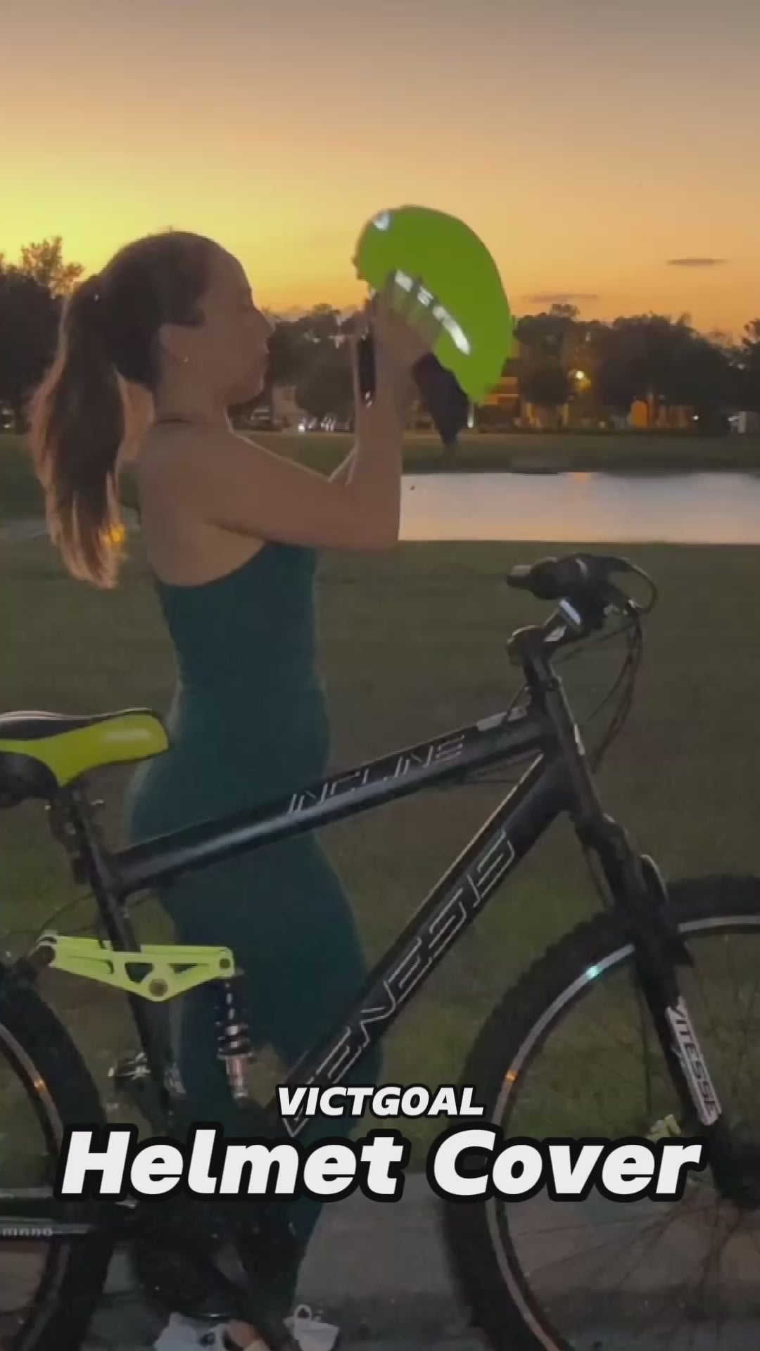 Rider holding a reflective bike helmet rain cover beside a bicycle at sunset